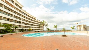 Un hotel con piscina, palmeras y vistas al océano.