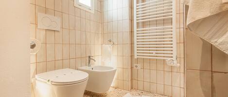 Une salle de bain équipée de toilettes, d’un bidet et d’un porte-serviettes.
