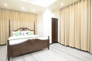 Quarto com cama de madeira, cortinas bege e uma porta.