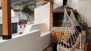 A covered patio area with a hammock, a grill, and a view of the surrounding landscape. - Kimsa Wasi (Otavalo)