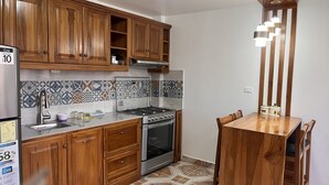 A kitchen with wooden cabinets, a gas stove, an oven, and a dining table with chairs. - Kimsa Wasi (Otavalo)