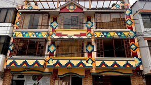 A multi-story building with colorful geometric patterns on the facade, balconies, and windows. - Kimsa Wasi (Otavalo)