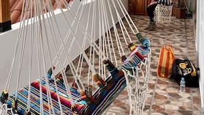 A hammock chair with colorful cushions, a stone-tiled patio, a wooden pergola, and a view of a coastal area. - Kimsa Wasi (Otavalo)