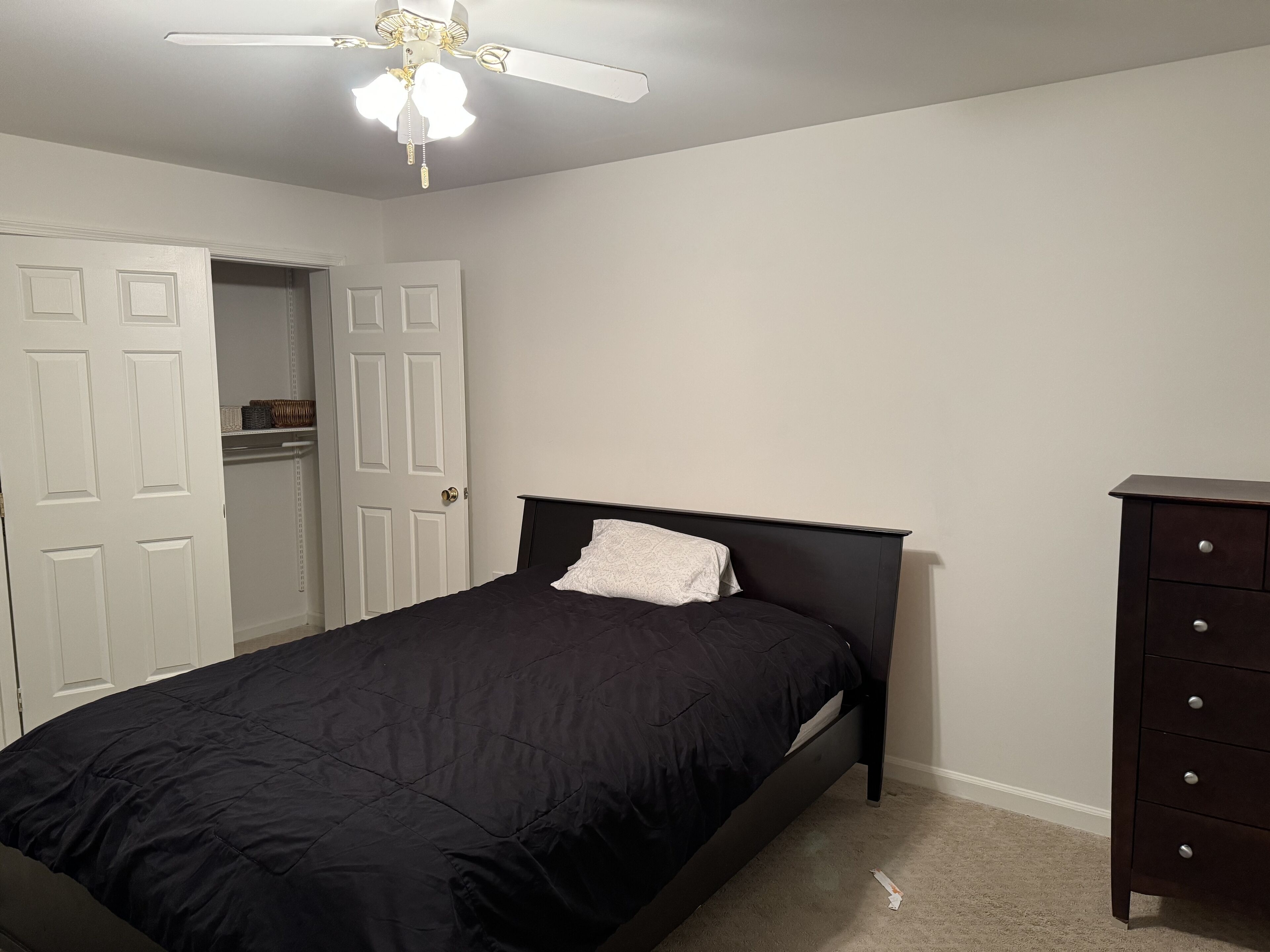 Une chambre à coucher avec un lit, une commode et un placard.
