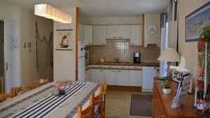 Una cucina con tavolo, sedie, una sveglia e una macchina per il caffè.