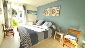 Una camera da letto con un letto, una sedia, un comodino e un quadro appeso al muro.