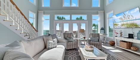 A spacious living room with a large sectional sofa, two armchairs, a coffee table, and a television on a stand.