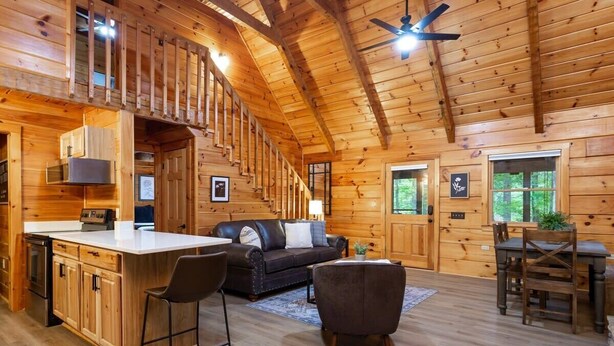 A spacious log cabin with a large kitchen, dining area, and a cozy living room with a staircase leading to a loft. - Stylish Cabin Near Pigeon Forge (Sevierville)
