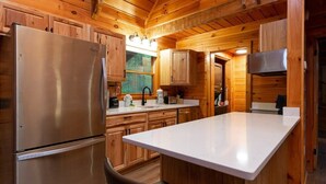 A modern kitchen with wooden cabinetry, a stainless steel refrigerator, and a central island. - Stylish Cabin Near Pigeon Forge (Sevierville)