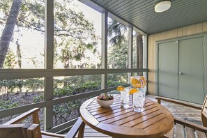 Una mesa de madera con un bol y bebidas en un balcón con vista a árboles.