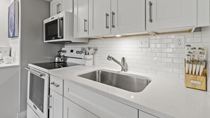Une cuisine moderne avec des meubles blancs, des appareils en acier inoxydable et un bloc à couteaux.