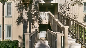 Un escalier en bois, doté d’une rampe, mène à l’entrée d’un bâtiment.