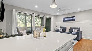 Une cuisine moderne dotée d’un grand îlot central, d’un coin repas et d’un salon avec un canapé et un téléviseur.