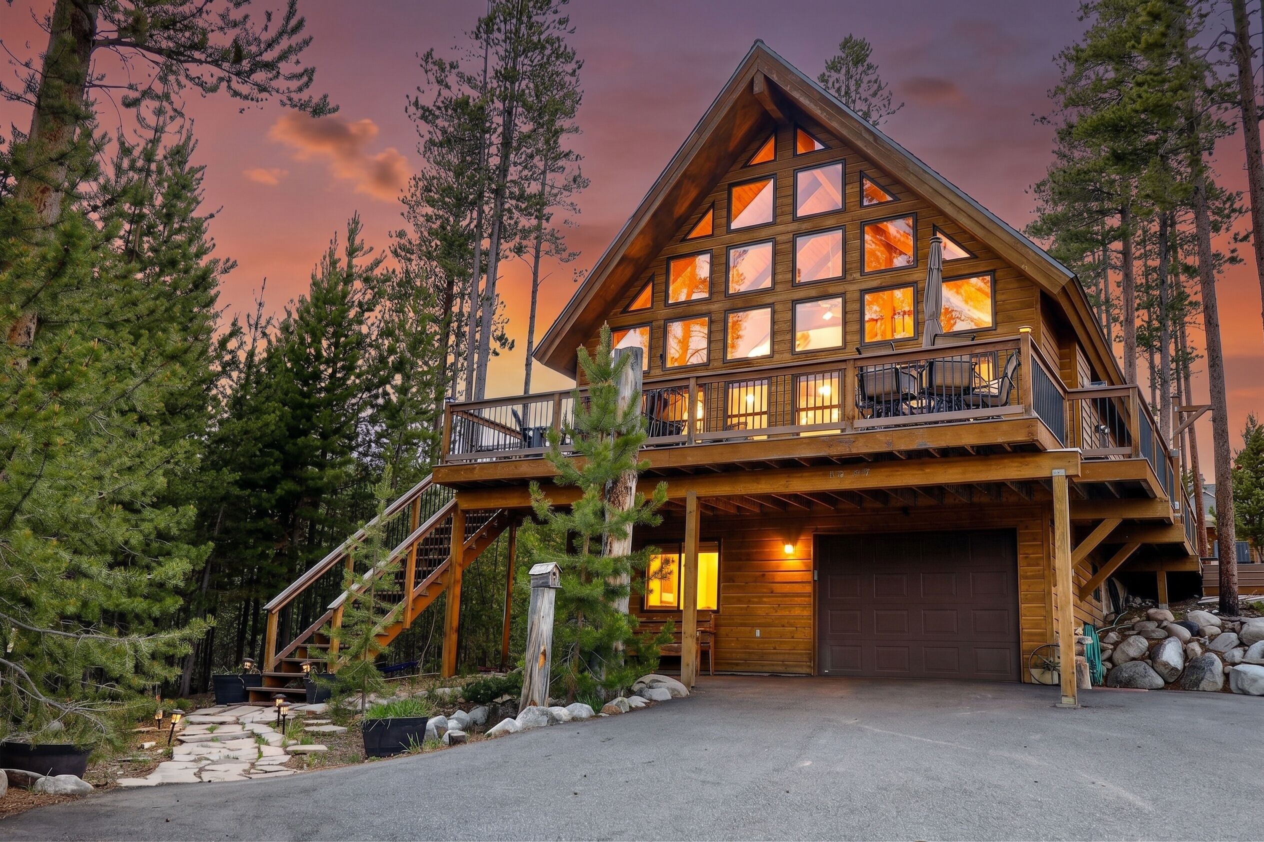 A two-story log cabin with a balcony, surrounded by trees.