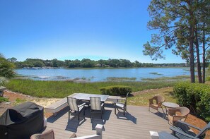 A deck with outdoor furniture overlooking a lake.