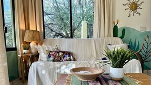 A cozy living room with a sofa, a wooden table with a bowl, a potted plant, and a wall mural. - El Nido - Paradise In Cabo Pulmo! 2 Bedroom Villa by RedAwning (Cabo Pulmo)