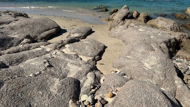 Una spiaggia rocciosa con grosse rocce e una vista libera sull'oceano.