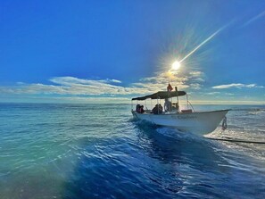 Un barco con pasajeros navegando en un mar tranquilo bajo un cielo despejado.