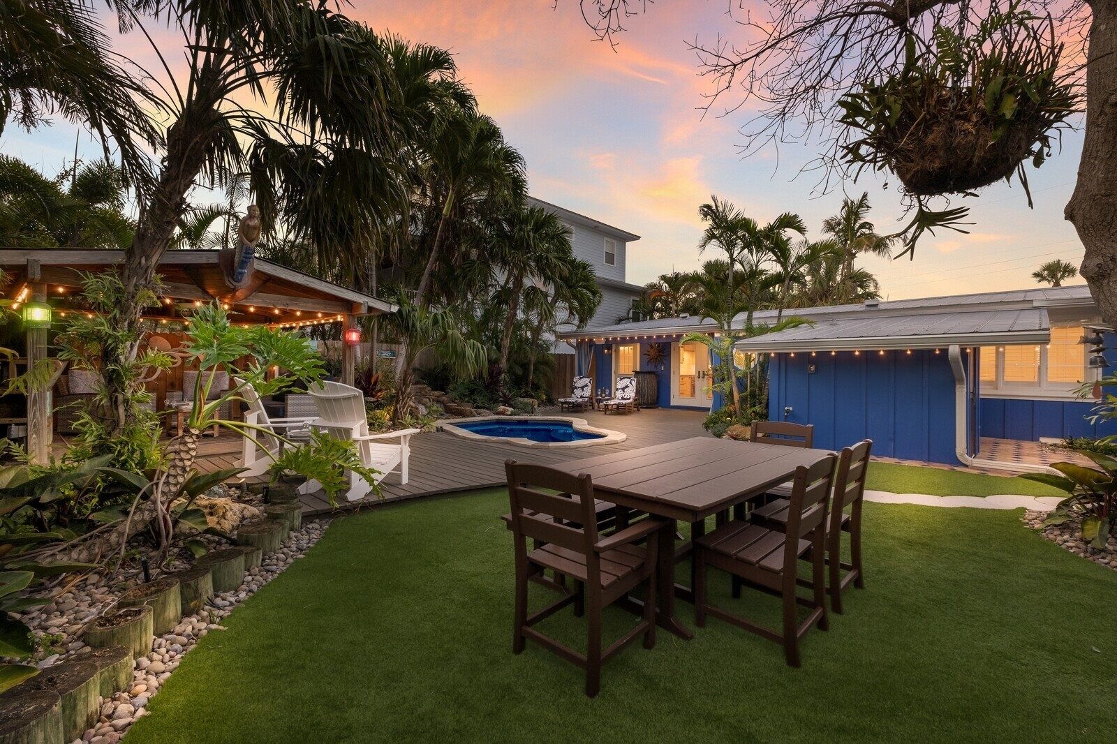 Un jardin avec une terrasse en bois, une piscine et un coin repas avec des chaises.