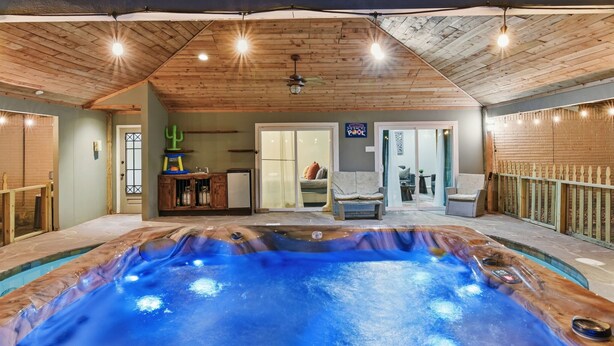 Een binnenzwembad met houten plafond en een hoek voor een jacuzzi.