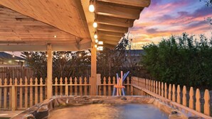 Een hottub onder een houten pergola, met een houten hek op de achtergrond.