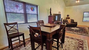 A dining area with a wooden table and chairs, a television, and a statue on a cabinet. - The Haven of Peace in Madison County, FL (Lee)