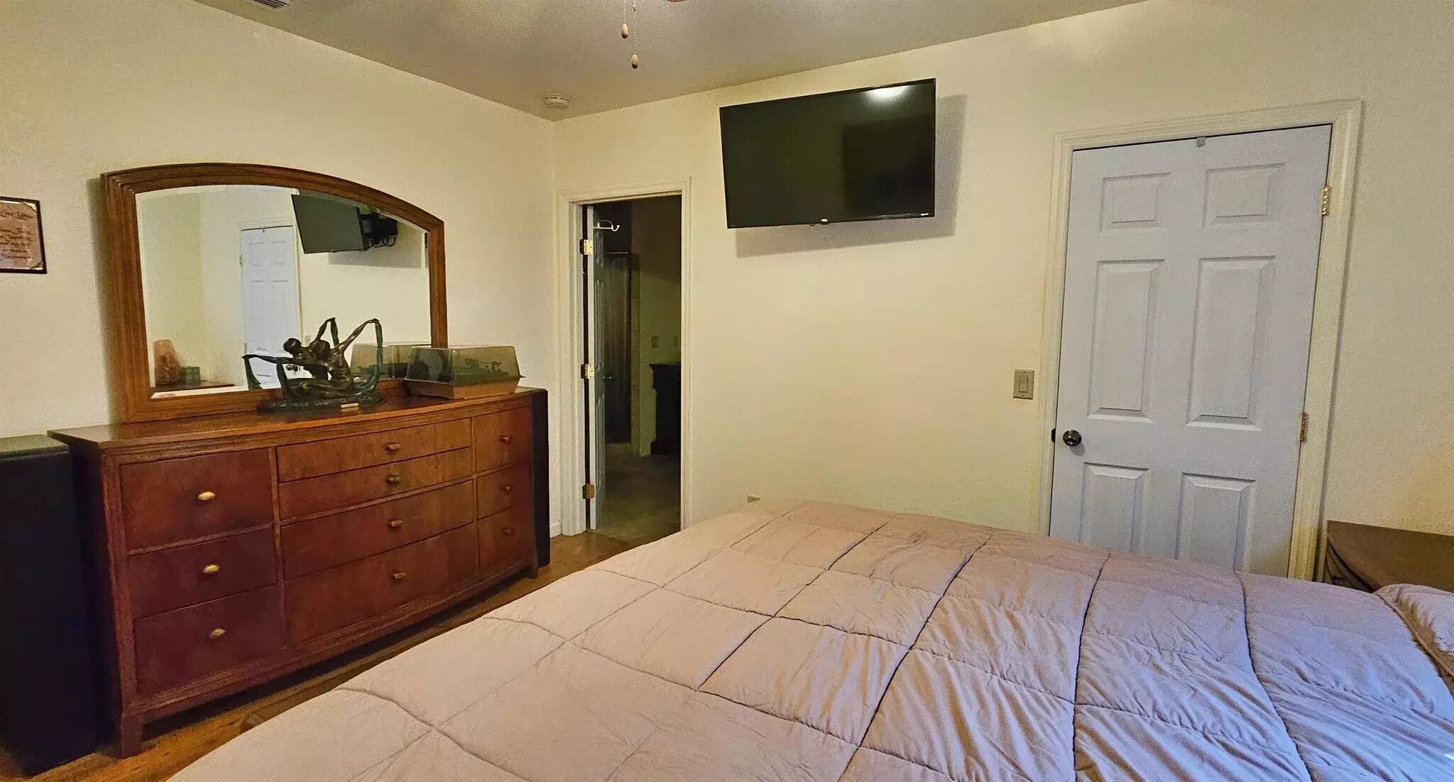 Camera da letto con un letto, una cassettiera, una TV e una porta.