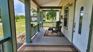 A covered porch with a bench and a door, leading to a grassy yard. - The Haven of Peace in Madison County, FL (Lee)