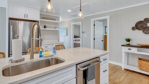 A modern kitchen with a stainless steel refrigerator, a double sink, and pendant lighting. - Modern Waterfront Cottage on Wilmington by Lucky Savannah (Savannah)