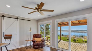 A room with a large sliding glass door leading to an outdoor deck with a view of a lake. - Modern Waterfront Cottage on Wilmington by Lucky Savannah (Savannah)