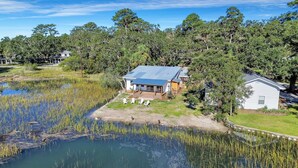 A house with a covered porch and a small dock extending into a pond. - Modern Waterfront Cottage on Wilmington by Lucky Savannah (Savannah)