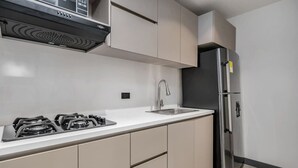 Una cocina moderna con estufa a gas, refrigerador de acero inoxidable y armarios color beige.