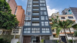 Un edificio moderno de varios pisos con una entrada destacada, grandes ventanales y un letrero visible que dice "Housu".
