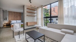 Una sala de estar moderna con un sofá, una mesa de centro y un televisor. Hay una ventana con cortinas, un panel de pared de madera y un estante montado.