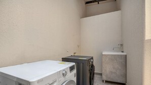 Uma área de lavanderia com máquina de lavar, secadora e uma pia pequena.