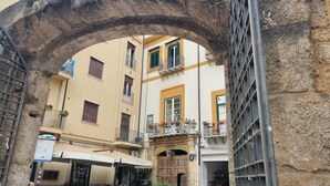 Un edificio con un arco de piedra, balcones con barandillas y un letrero de un negocio.