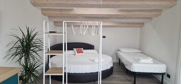 Una habitación pequeña con literas, una cama individual y una mesita.