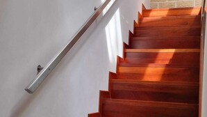 Una escalera de madera con barandilla de metal que conduce a un muro de ladrillo.