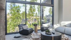 Een moderne woonkamer met een groot raam, leren banken, een ronde salontafel en een vloerkleed met giraffeprint.