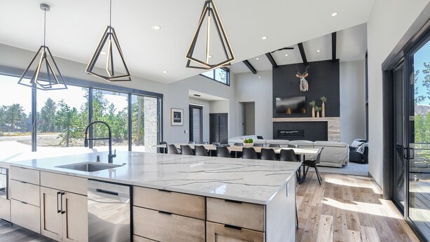 Een moderne keuken met een groot eiland, een zithoek met een bank en een open haard.