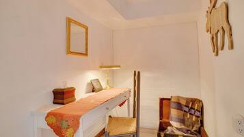 A room with a bed, a bedside table with a lamp, a mirror, and a wall-mounted wooden animal decoration.