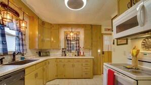 A kitchen with yellow cabinets, a microwave, a coffee maker, and a red towel hanging on the oven. - Harmony Home w/ Fire Pit: 5 Mi to Niagara Cave! (Harmony)