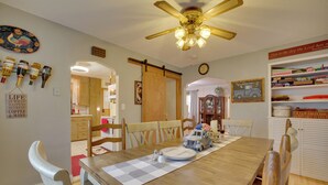 A dining area with a wooden table, chairs, a ceiling fan, and a kitchen in the background. - Harmony Home w/ Fire Pit: 5 Mi to Niagara Cave! (Harmony)