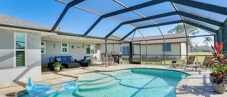 Una piscina exterior techada con zona de patio, que incluye asientos y una instalación para barbacoa.