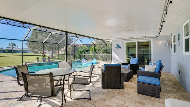 Un patio couvert avec une piscine, du mobilier d’extérieur et une vue sur le paysage environnant.