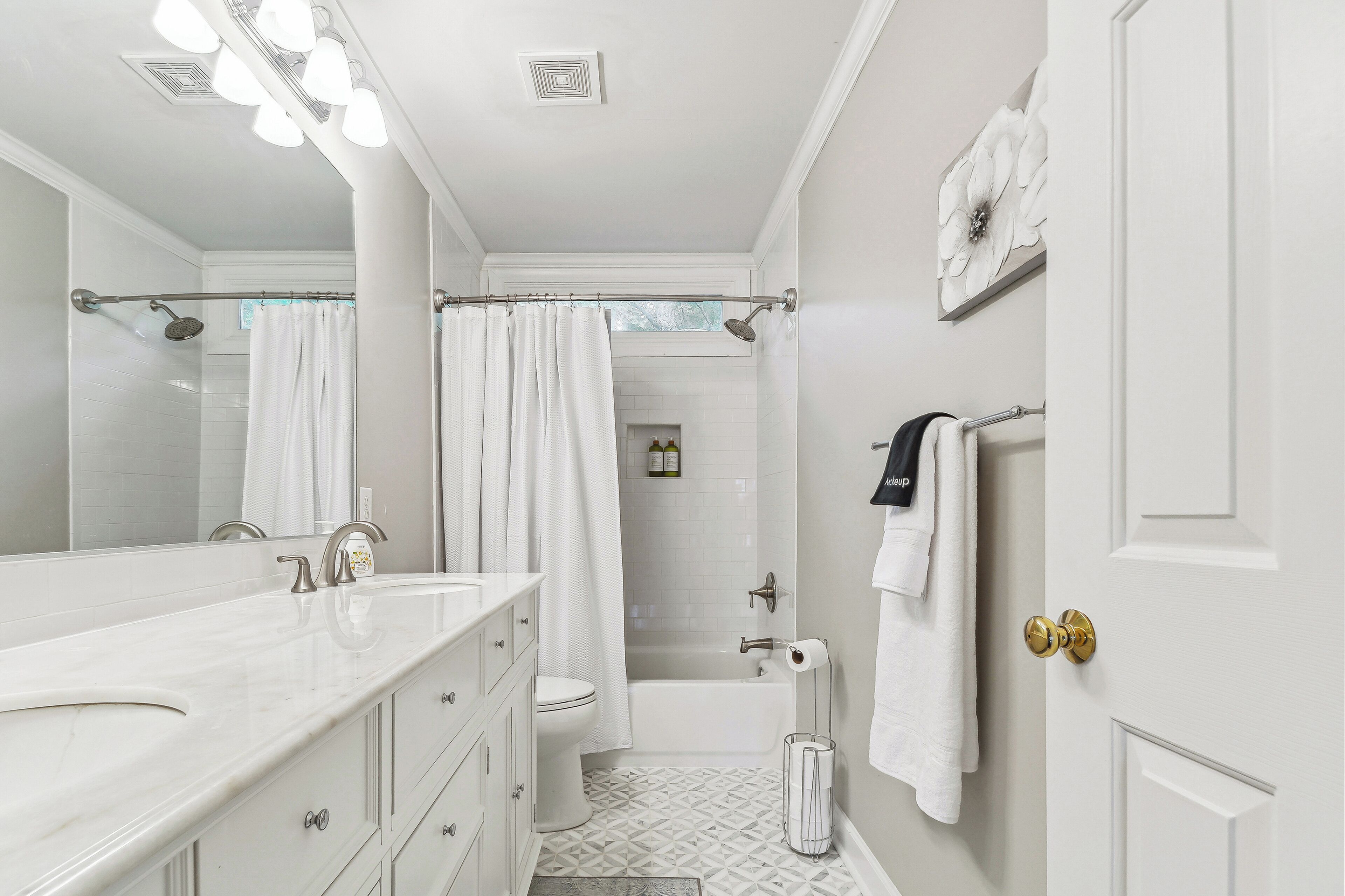 A bathroom with a large mirror, white fixtures, a shower, and a toilet.