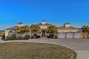 A large, single-story house with a central entrance, multiple garage doors, and a well-maintained lawn.