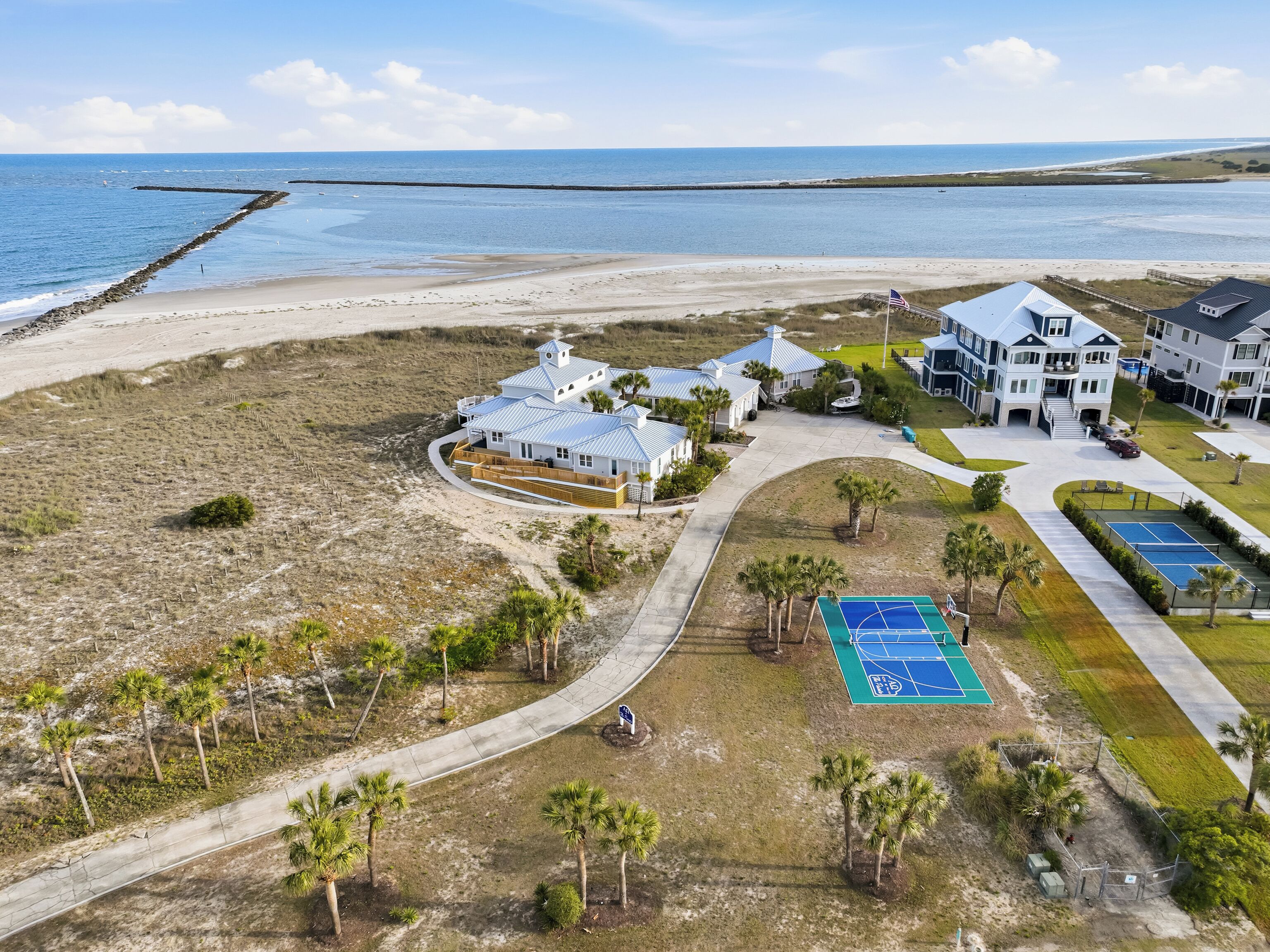 A coastal property with multiple buildings, a tennis court, and a beach access.
