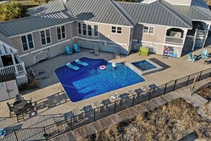 A residential property with a swimming pool, outdoor seating, and a fenced deck area.