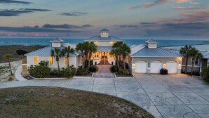 A beachfront house with a driveway, palm trees, and a view of the ocean. - Alpha At The Point: Oceanfront, Private Pool & Hot Tub, Breathtaking Views (Garden City Beach)